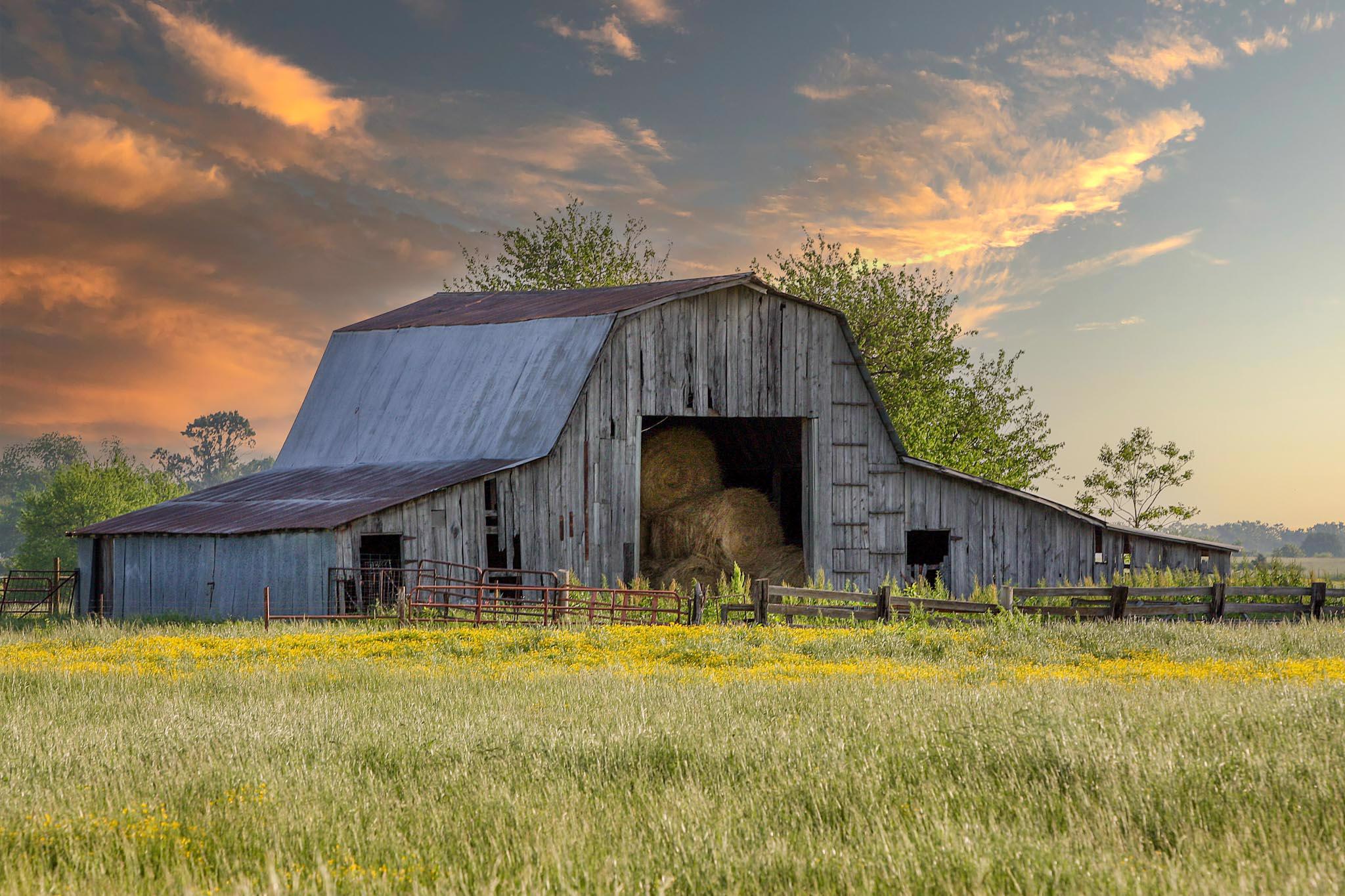 Old barn in field at sunset