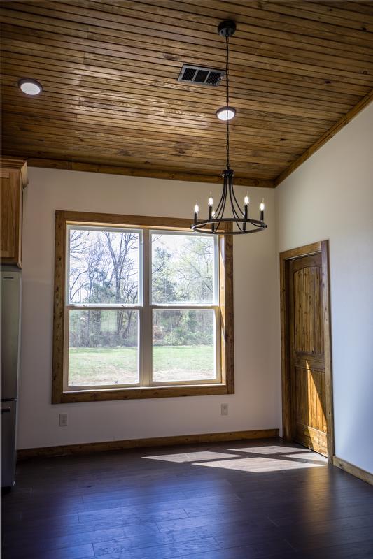 Large kitchen window next to dining area which features black metal chandelier