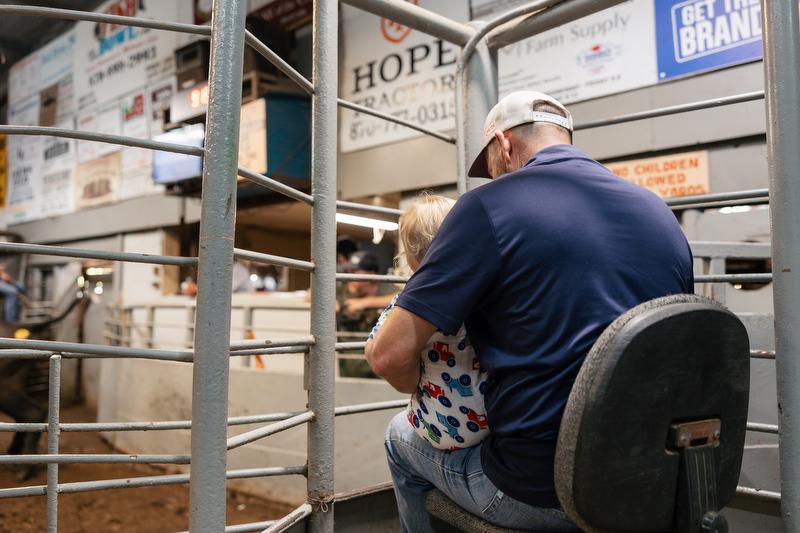 Darrell Ford works the gates at the Hope Livestock Auction with his grandson (Glen's great-grandson) in his lap.