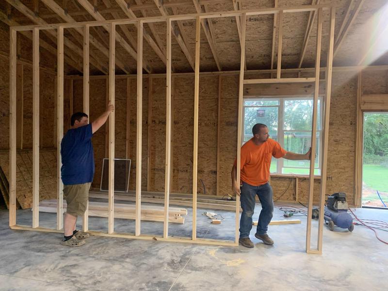 Two men put up framing inside home