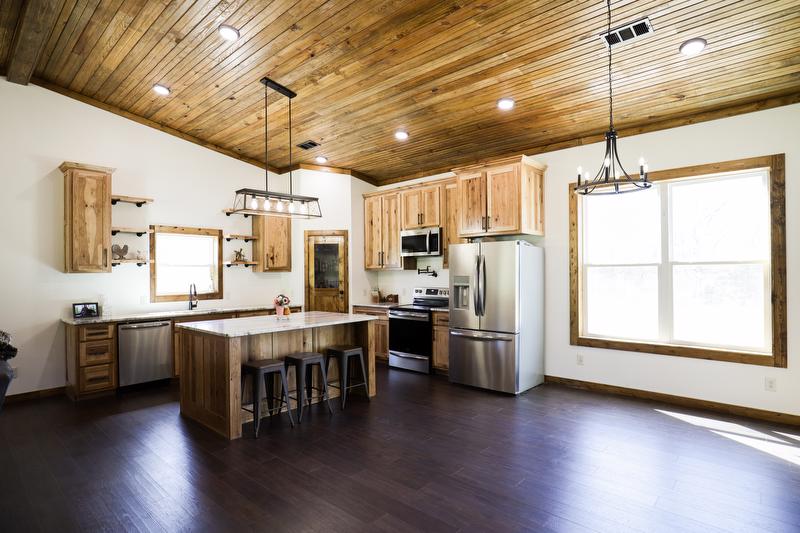 Wide angle view of kitchen featuring custom cabinets, large island, and dining area with large window