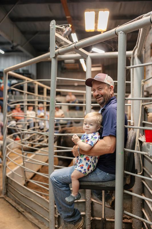 Darrell Ford works the gates at the Hope Livestock Auction with his grandson (Glen's great-grandson) in his lap.