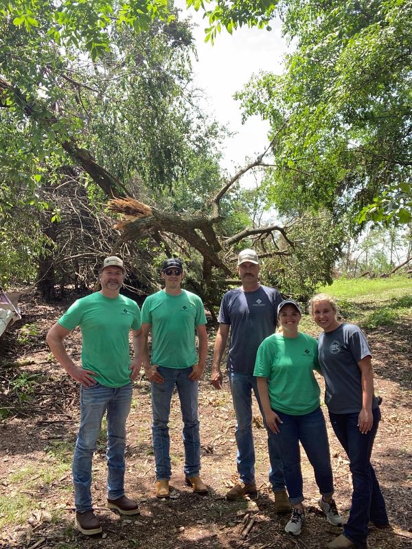 Farm Credit of Western Arkansas employees stand in front of downed tree