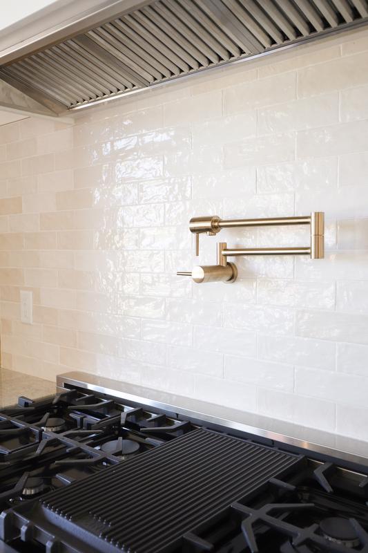 Gold finish pot filler above the stove.