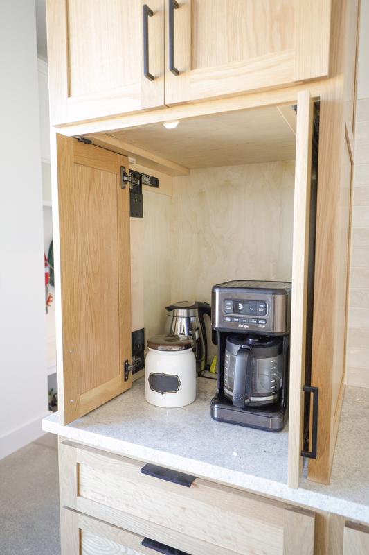 Coffee pot and supplies inside a cabinet with receding doors