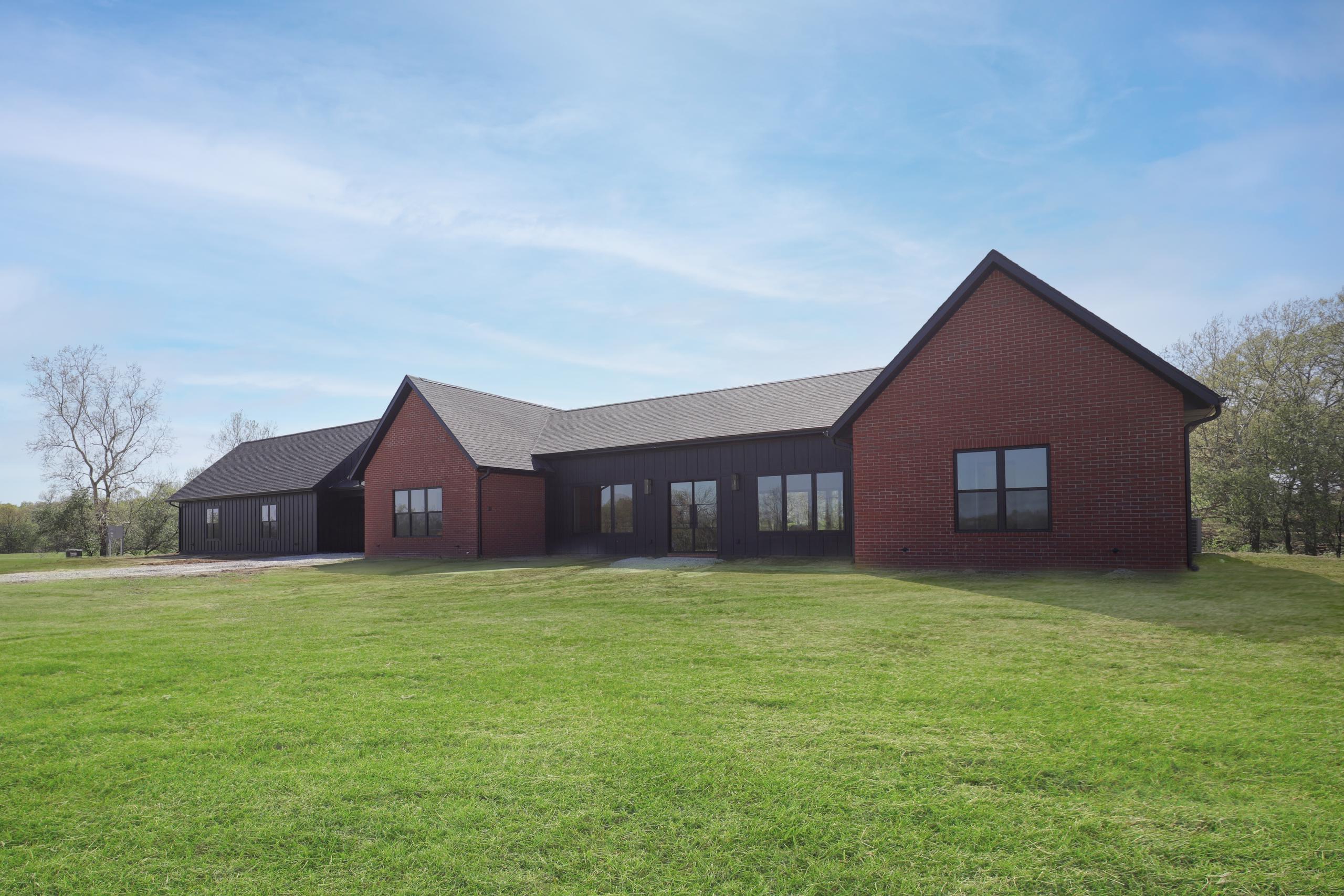 Exterior of red brick and black siding home.