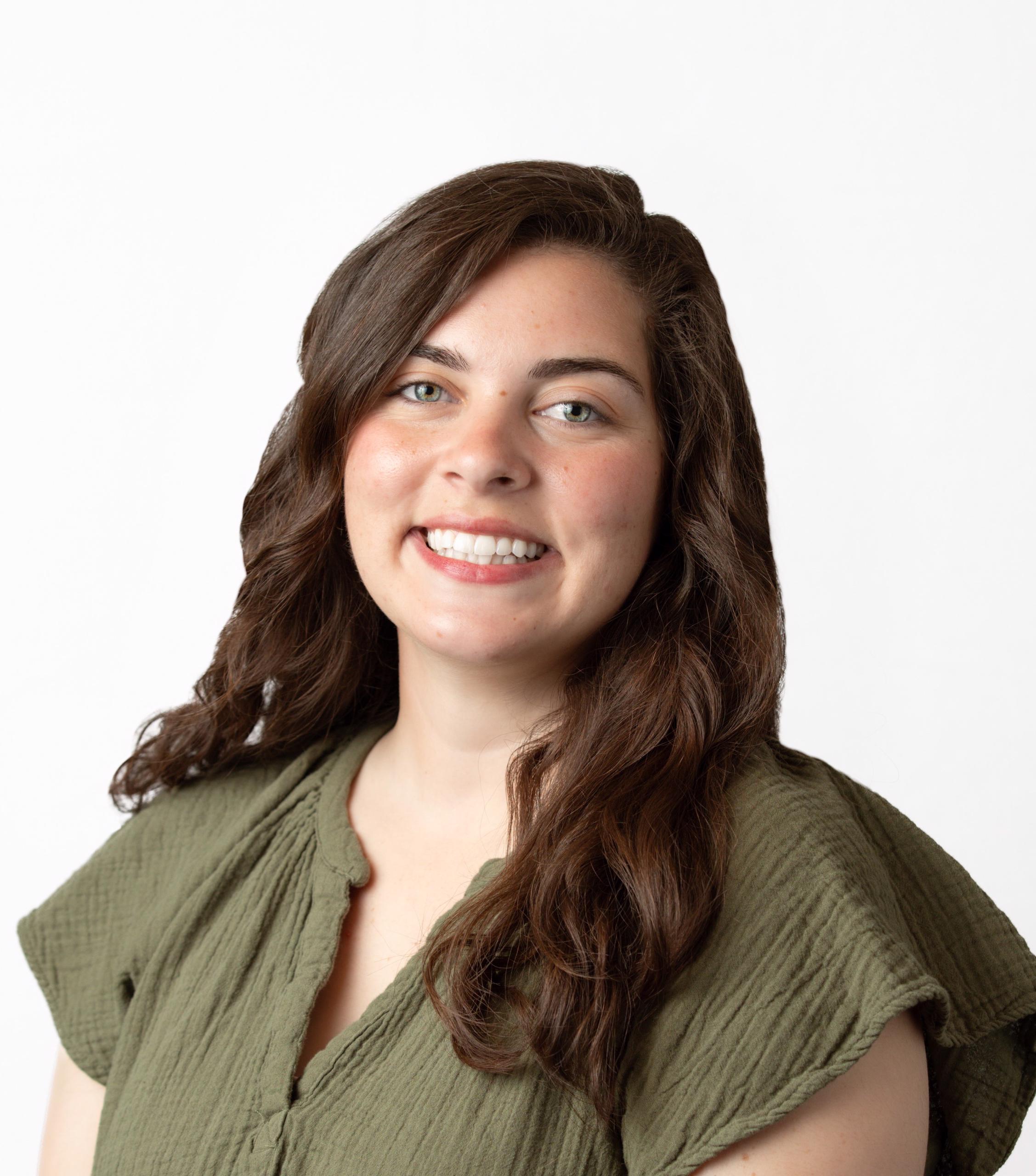 Person with brown hair and green shirt smiles for headshot